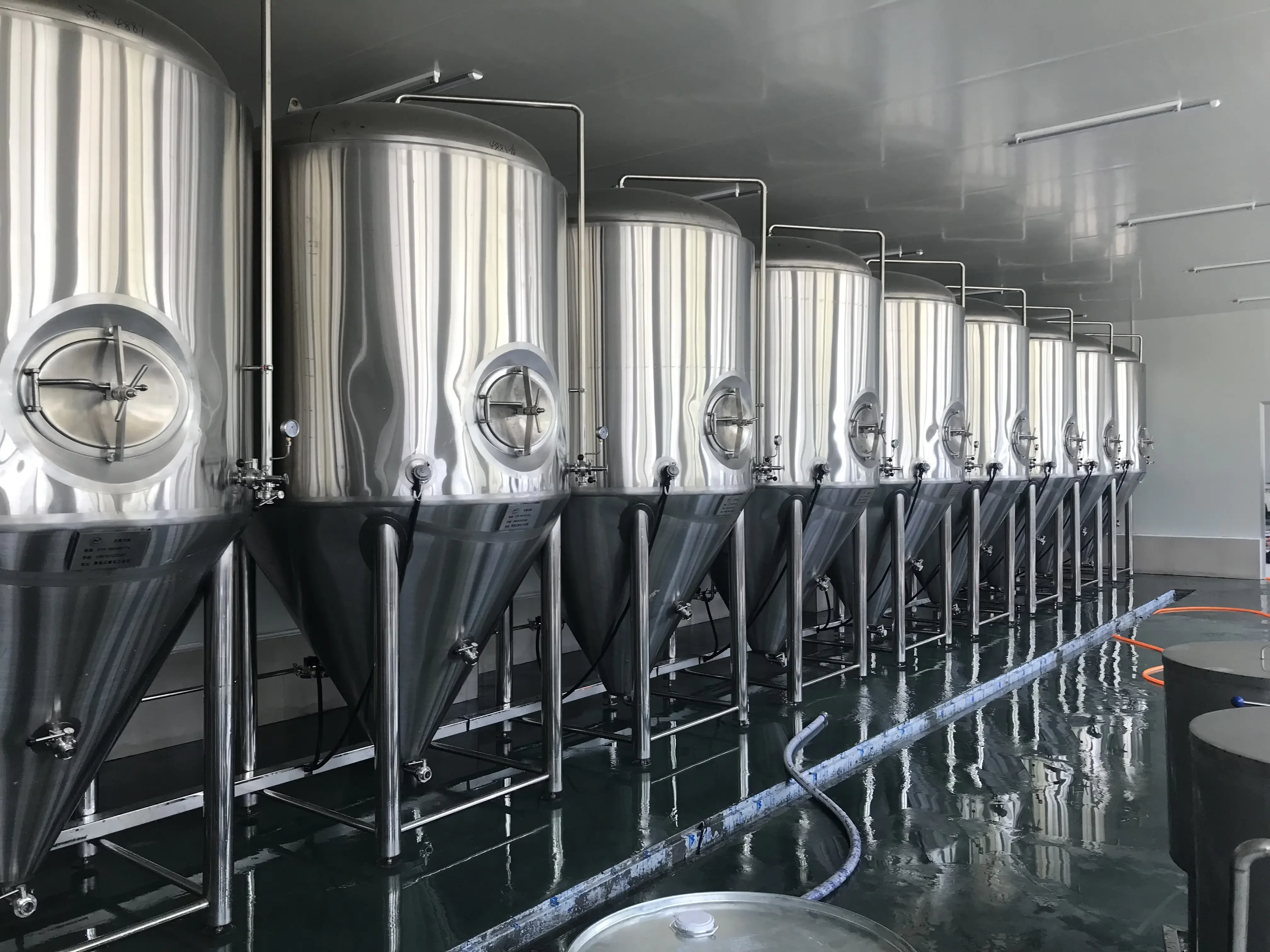 小型散装啤酒生产设备间实景，展示不锈钢发酵罐、糖化锅及管路连接_1