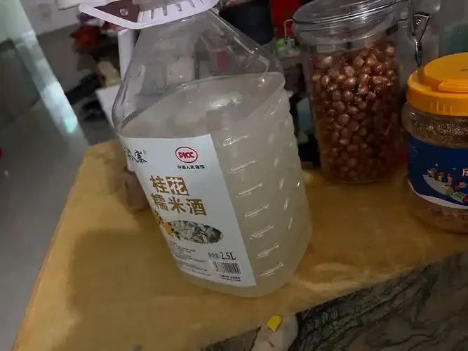 酿酒师傅在传统作坊中查看糯米发酵酒醅状态的实景照片_1