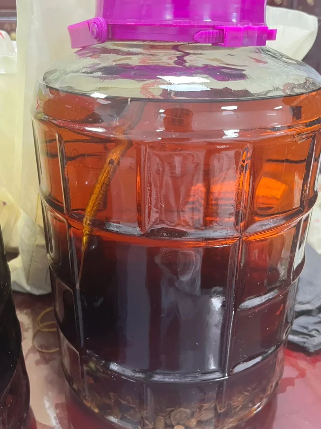 正在浸泡中的自制祛风湿药酒，玻璃罐内可见多种中药材，酒色醇厚，旁边摆放着备用的药材。_1