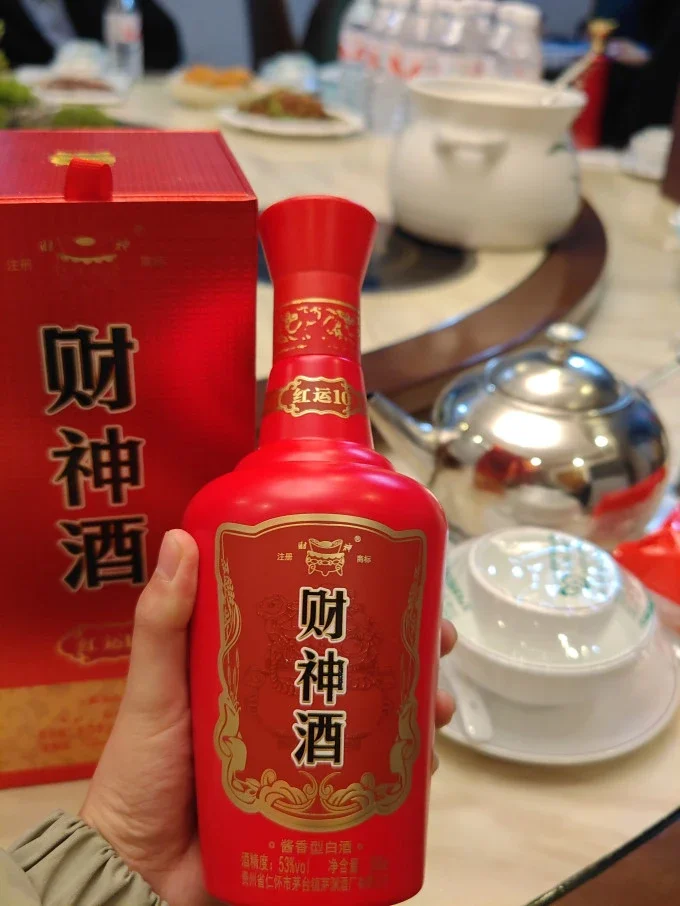 几种公认性价比高的光瓶白酒摆放在木桌上，包括汾酒、西凤酒和二锅头，旁边配有品酒杯。_1