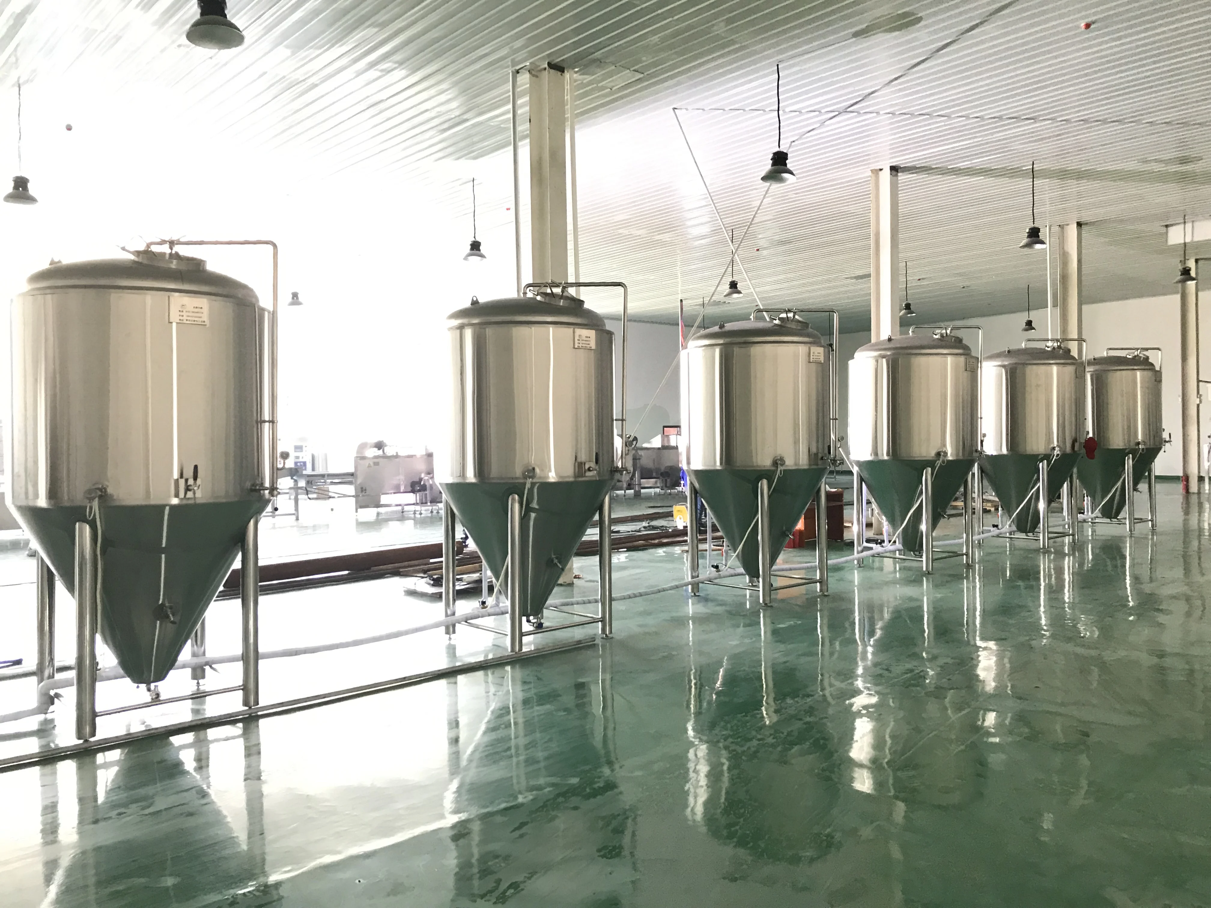 一套完整的现代化不锈钢精酿啤酒设备，包括糖化罐、煮沸罐和发酵罐，展示在精酿啤酒馆的环境中。_1