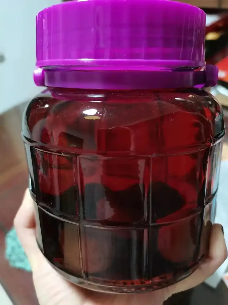 自制杨梅泡酒成品展示：透明玻璃罐中琥珀色酒液浸泡着饱满的杨梅，旁边伴有新鲜杨梅和冰糖。_1