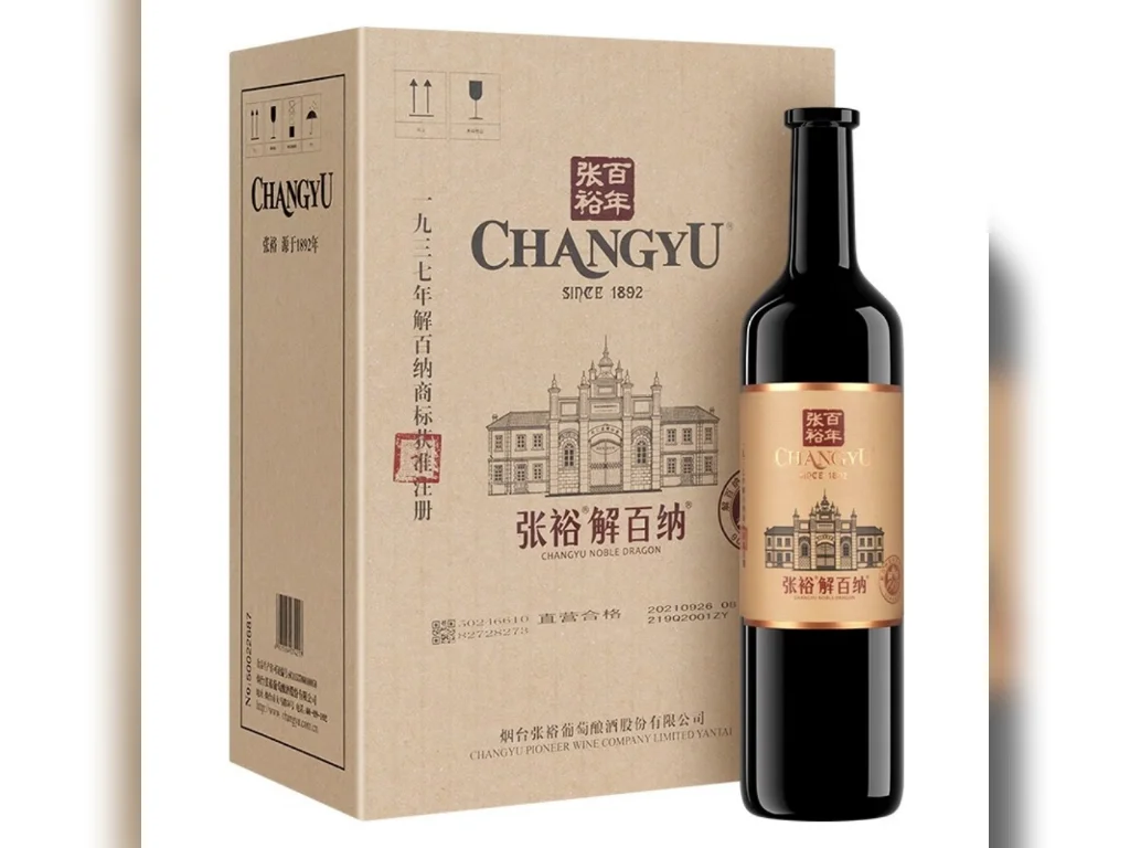 张裕百年干红葡萄酒静物展示：酒瓶与酒杯，背景为橡木桶和酿酒笔记_1