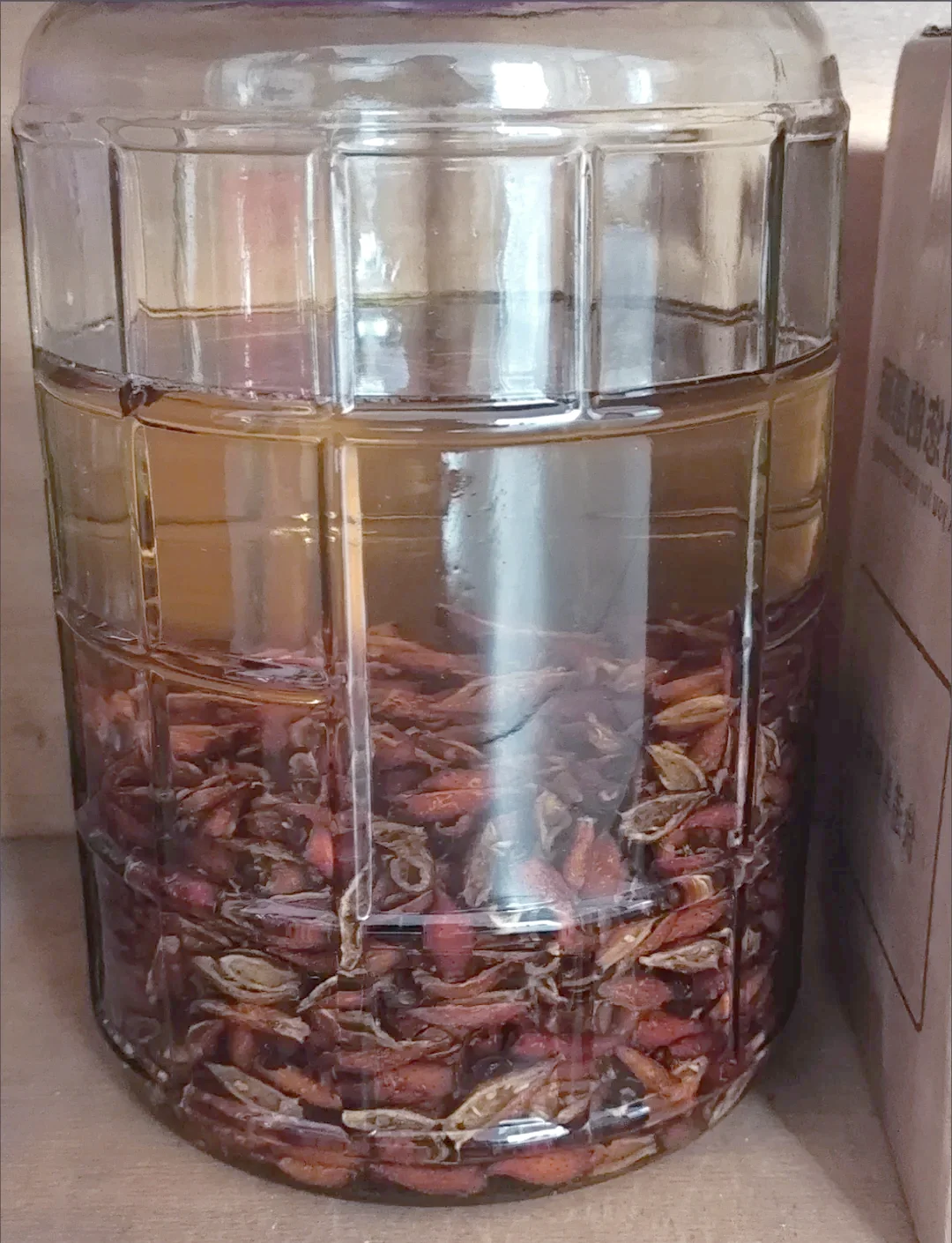家庭自酿金樱子泡酒特写：玻璃罐中琥珀色酒液与深红色金樱子果实_1