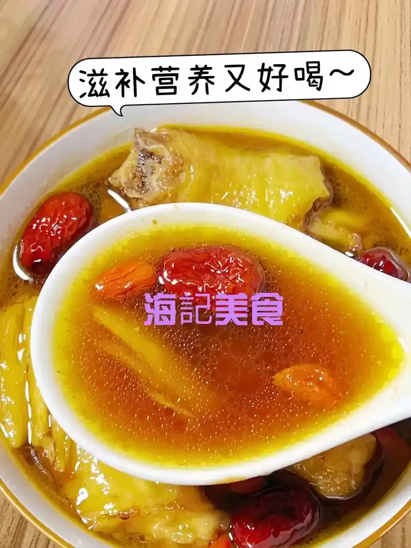 一锅热气腾腾的黄酒煮鸡汤特写，汤汁金黄，鸡肉软烂，配以黄酒瓶和红枣生姜作为装饰。_1