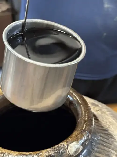 一碗盛在古朴陶碗中的冬酿酒，酒色清亮微黄，旁边点缀着枫叶与梅花，散发出冬日温暖的酿造气息。_1