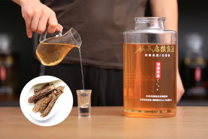 肉苁蓉党参泡酒成品展示，透明玻璃罐中淡琥珀色酒液清晰可见，旁边散落着泡酒所用的肉苁蓉、党参和枸杞。_1